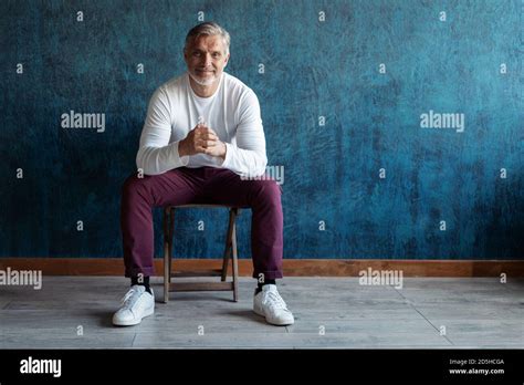Portrait Of A Casual Grey Haired Mature Handsome Man Sitting On A Chair