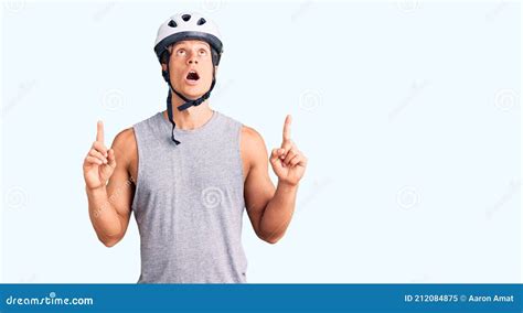 Young Handsome Man Wearing Bike Helmet Amazed And Surprised Looking Up