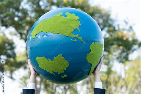 Earth Day Concept With Big Earth Globe Held By Hand Up In Sky To