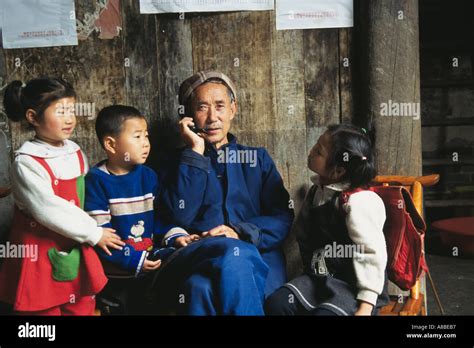 Old Man Using Cellular Phone In Ancient House With Grandchildren Around