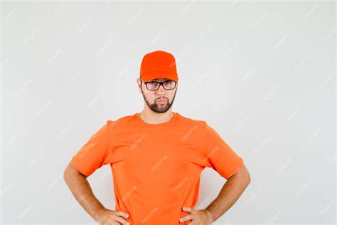 Free Photo Delivery Man In Orange T Shirt Cap Standing With Hands On