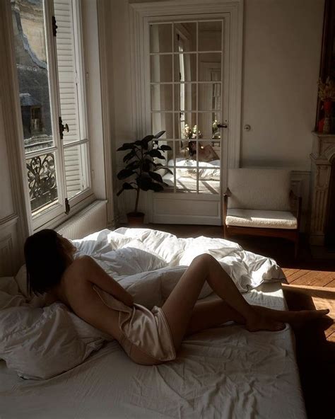 A Naked Woman Laying On Top Of A Bed In A Bedroom Next To A Window