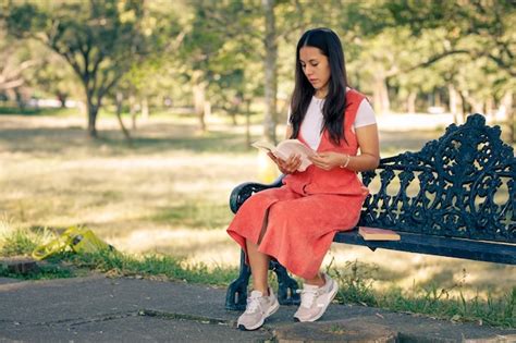 Premium Photo Mujer Latina Sentada En Una Banca De Un Parque Leyendo