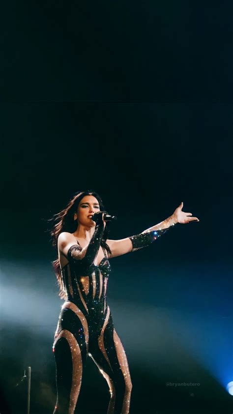 a woman in black and white outfit on stage with her arms out to the side