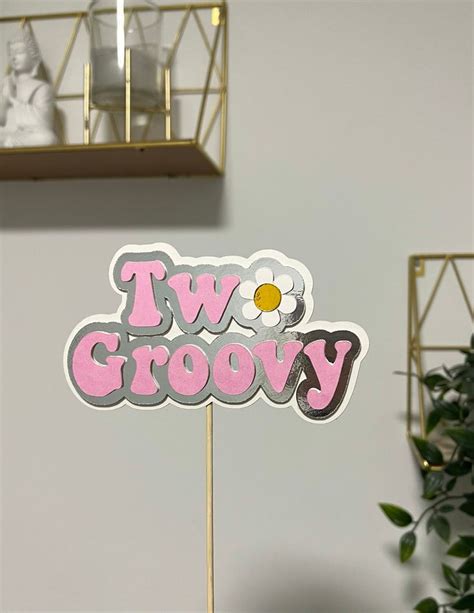 A Cake Topper That Says Two Groovy With A Flower In The Middle