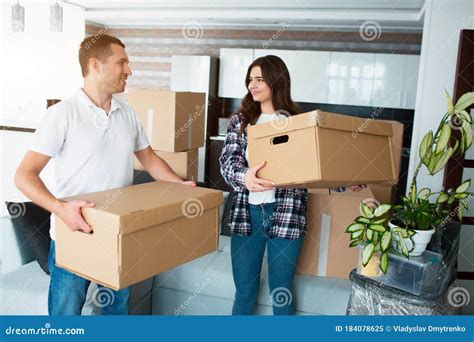 Young Couple Carrying Big Cardboard Box At New Home Moving House Stock