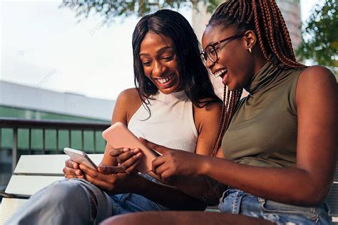 Two Young Women Laughing While Looking Phones Adult Teenager American