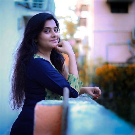 A Woman Leaning Against A Wall With Her Hand On Her Chin And Looking At