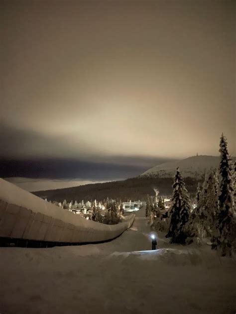 The Night Sky Is Dark And Cloudy Over Some Snow Covered Trees