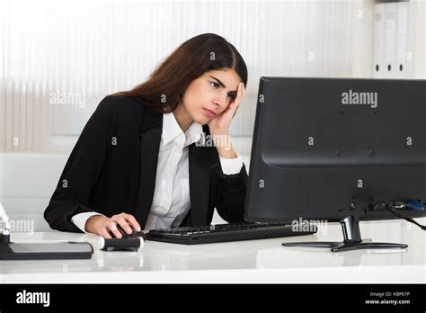 Stressed Young Businesswoman Using Computer At Desk In Office Stock