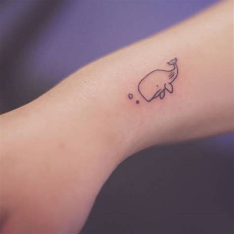 Small whale tattoo on the right wrist.