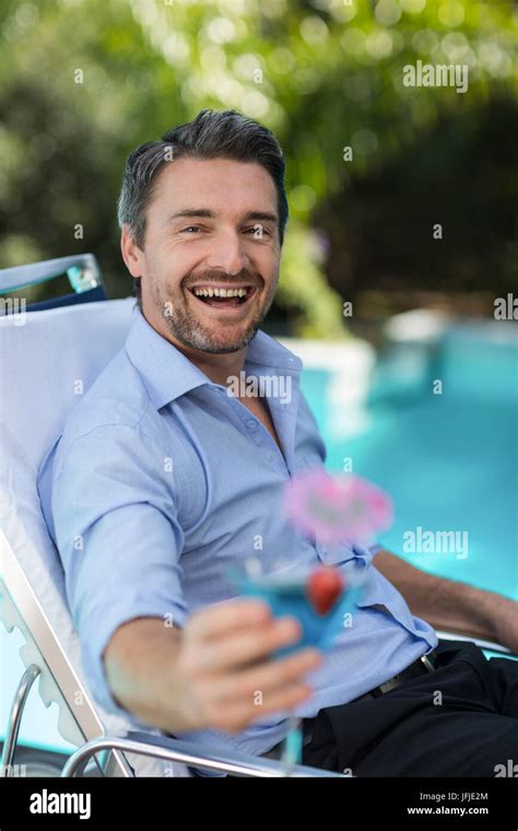 Smart Man Holding Martini Glass While Relaxing In Sun Lounger Stock