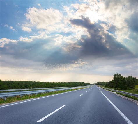 Asphalt Road Leaving Far Under Dense Cloudy Sky and Sun Stock Image - Image of transport ...