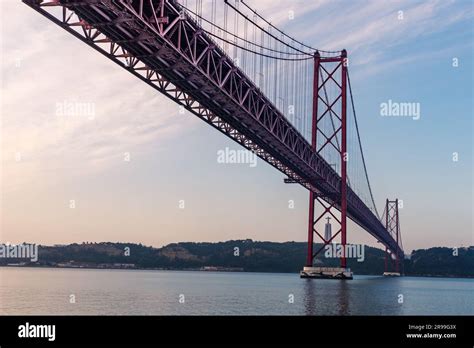 25 De Abril Bridge At Sunrise With The Cristo Rey De Almada Monument In