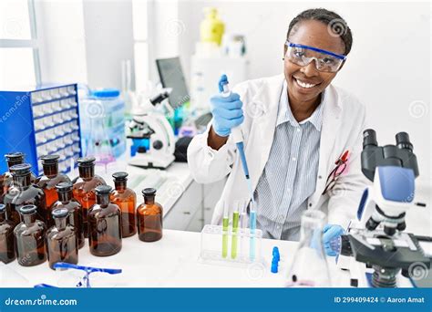 African American Woman Scientist Pouring Liquid On Test Tube At