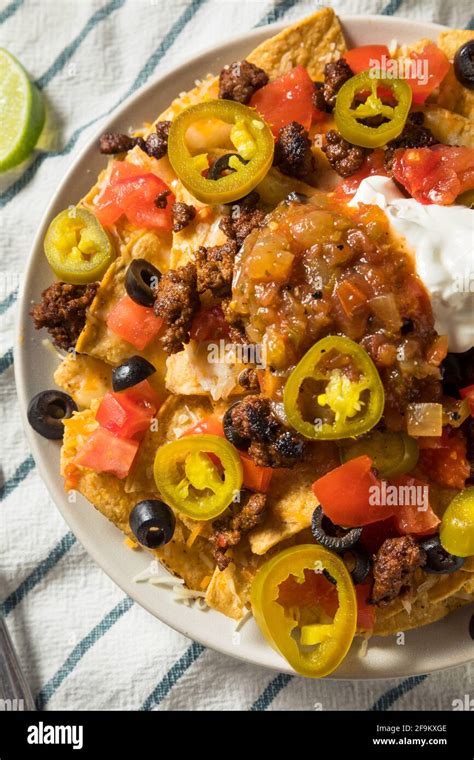 Homemade Cheesy Beef Nachos with Olives and Jalapenos Stock Photo - Alamy