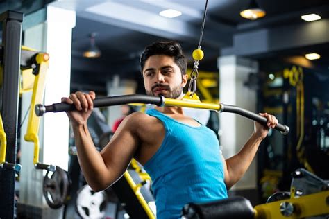 Homem bonito asiático indiano malhando ou se exercitando na academia