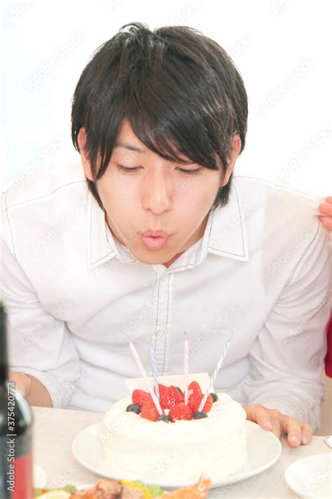 誕生日ケーキのロウソクの火を消す男性 Stock Foto Adobe Stock