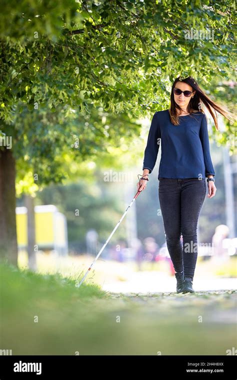 Blind Woman Walking On City Streets Using Her White Cane To Navigate