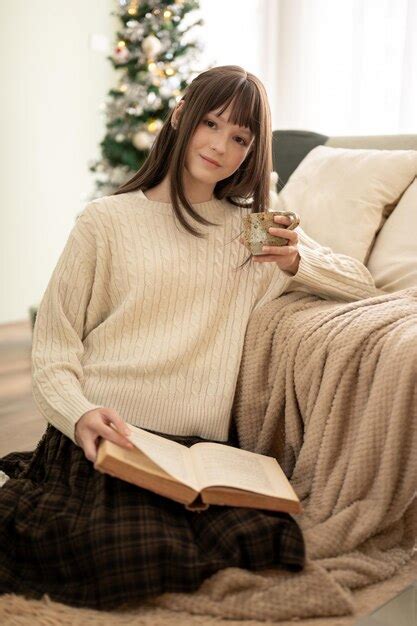 Premium Photo A Pretty Woman In Cosy Clothes Is Reading A Book And