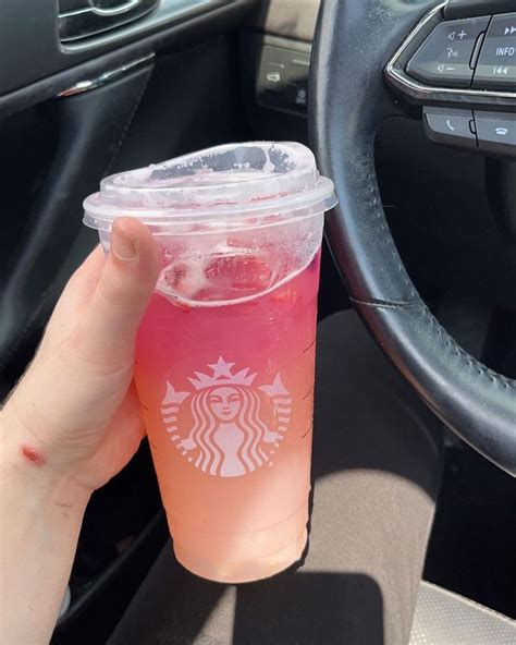 A Person Holding Up A Plastic Cup With Pink Liquid In The Middle Of