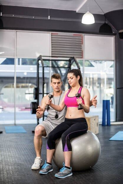 Premium Photo Male Trainer Assisting Woman Lifting Dumbbells At Gym