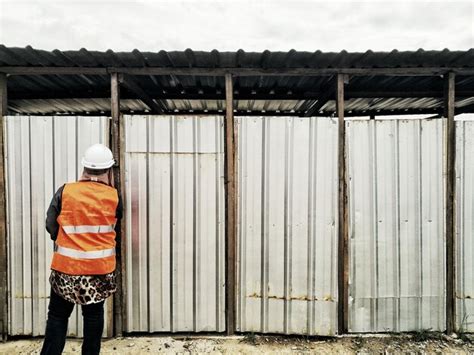 Premium Photo Rear View Of Worker Standing Against Corrugated Iron Doors