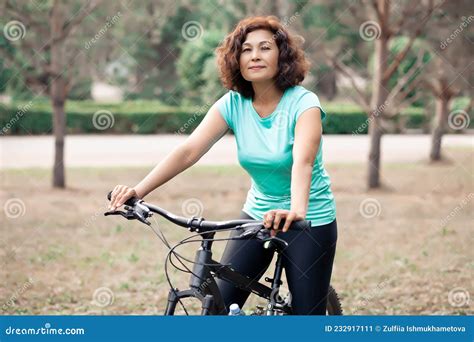 Middle Age Senior Woman On Bike Cycle Ride In Countryside Park Outdoor