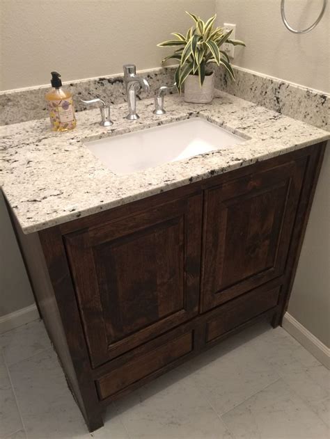 a bathroom vanity with marble counter top and wooden cabinetry in front ...