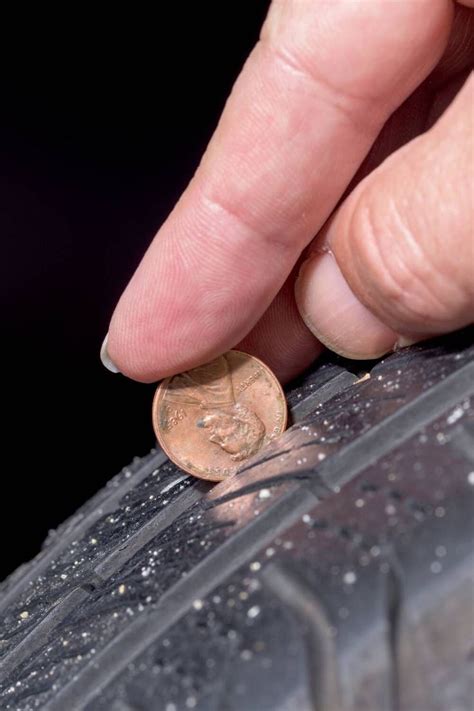 a close up of a person's hand touching a coin on top of a tire