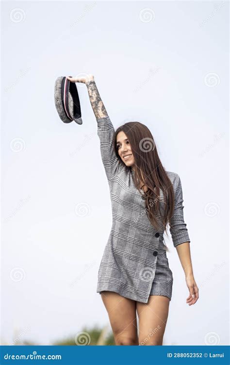 Youthful Urban Elegance A Confident Brunette In A Short Dress And Hat