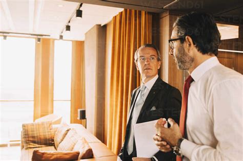 Mature Financial Advisors Talking While Walking In Corridor At Law