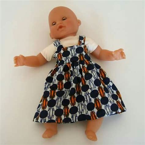 A Baby Doll Wearing A Blue Dress And White T Shirt With Orange