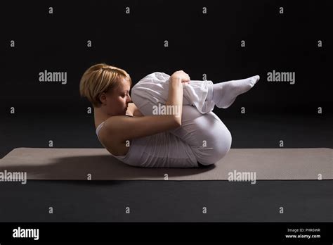 Woman Exercising Yoga Indoor On Black Background Wind Relieving Pose