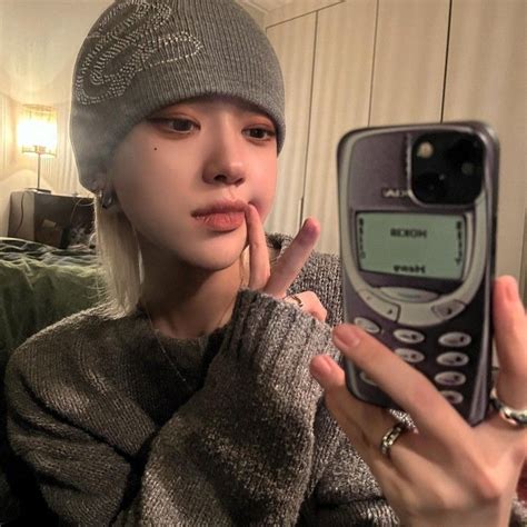 A Woman Holding Up A Cell Phone In Front Of Her Face While Wearing A Beanie