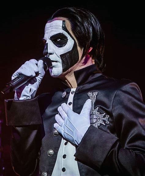 A Man With Black And White Face Paint Holding A Microphone