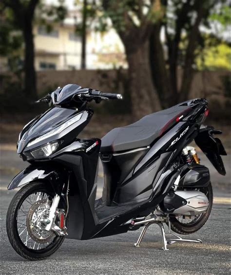 A Black Motorcycle Parked On Top Of A Parking Lot Next To Trees And