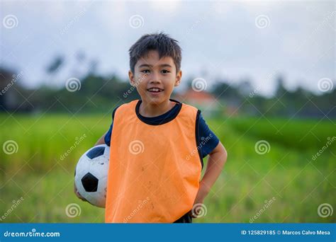 Lifestyle Portrait Of Handsome And Happy Young Boy Holding Soccer Ball