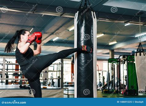 Athletic Girl Makes A Kick On The Punching Bag Woman In Boxing Gloves