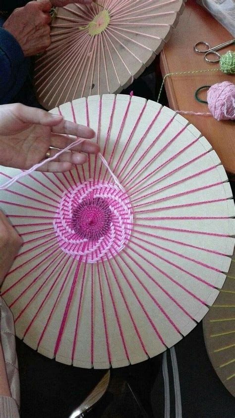 The Woman Is Working On Her Craft With Pink And White Parasols In Front