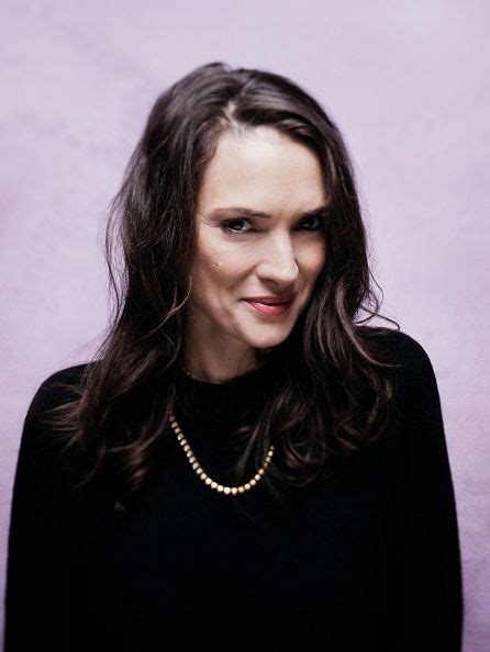 A Woman With Long Hair Wearing A Black Shirt And Pearls Necklace