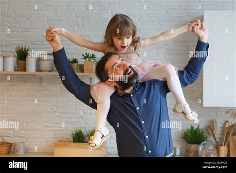 Happy Little Daughter Sitting On Father Neck Piggybacking Playing