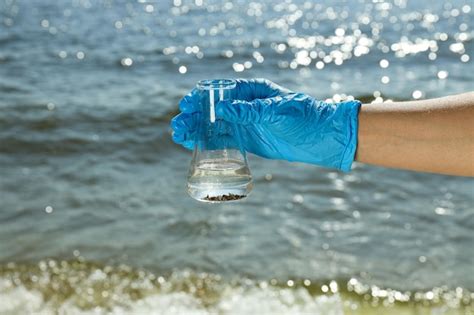 Un tubo de ensayo con agua de río en manos con guantes azules Foto