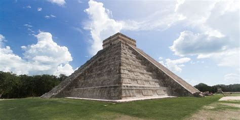 An Ancient Pyramid In The Middle Of A Grassy Area Under A Blue Sky With