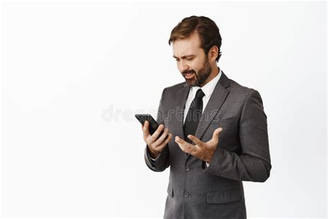 Confused Businessman Looking At His Mobile Phone Screen Having Problem