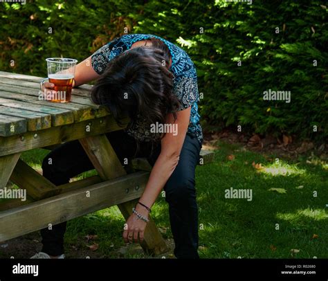 A Drunk Woman With A Glass Of Beer In Her Hand Unconscious Leaning On