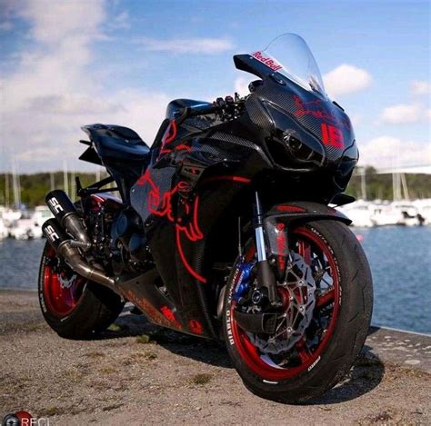 A Red And Black Motorcycle Parked Next To The Water