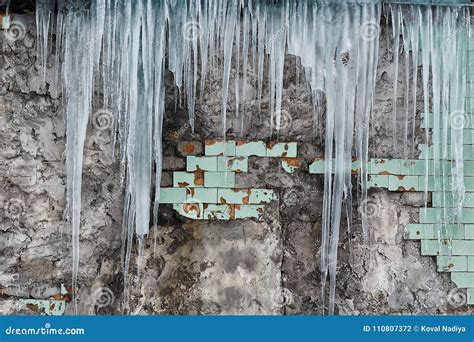 Icicles Hanging From The Roof Of The Old Brick Building With Cubes Of