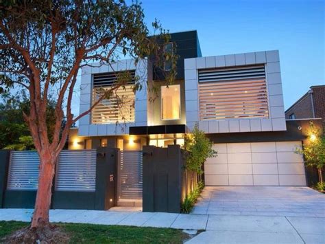 A Modern House Is Lit Up At Night With Lights On The Front And Side Windows