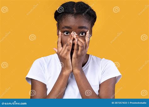 Shy African Woman Looking At Camera Through Fingers Yellow Background Stock Image Image Of